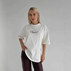 Détail du t-shirt blanc en coton avec lettrage noir Cheers et texture de tissu doux