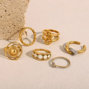Detail of 18K gold-plated twisted rings and opal stone set on a natural stone background