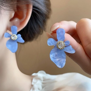 Dettaglio orecchini a fiore in resina blu con zirconi scintillanti e base dorata
