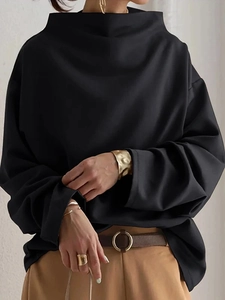 Close-up of black loose-fit turtleneck top showing detailed fabric texture and drop shoulder