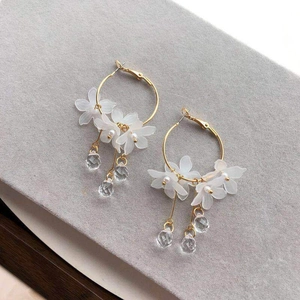 Elegant gold hoop earrings with matte white flowers and sparkling crystal teardrops