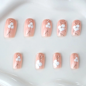 Faux ongles rose pêche avec motifs floraux blancs et petits pois, forme courte et carrée