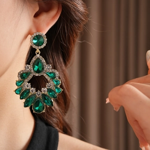 Gros plan sur les boucles d'oreilles vintage en or avec pierres vertes et strass