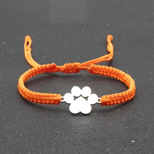 Detail of adjustable orange woven bracelet with silver metal paw print charm