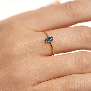 Macro shot of 18k gold ring with marquise cut blue zircon stone on a model hand