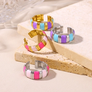 Macro view of colorful enamel striped adjustable rings on beige textured stone slabs
