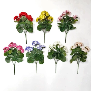 Flat lay of artificial geranium silk flowers in seven colors on a white background