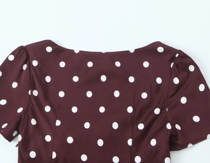 Detail of burgundy polka dot dress featuring a classic boat neckline and smooth fabric