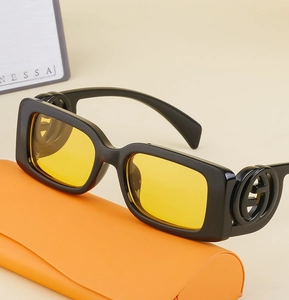 Detail of square black sunglasses with yellow lenses and metallic logo on temple