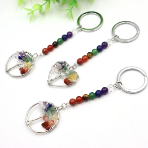 Three colorful tree of life crystal keychains with chakra stones on a white background