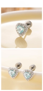 Close-up of heart-shaped blue zircon earrings with sparkling stones on silver studs