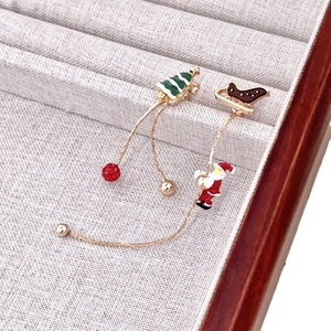 Détail macro de boucles d'oreilles de Noël asymétriques avec Père Noël et sapin