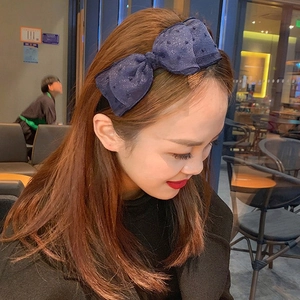 Navy blue polka dot headband with sequins worn by a woman in a natural cafe setting
