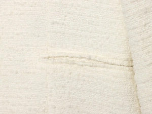 Detailopname van witte tweed stoftextuur en horizontale zakstiksels op de elegante jas
