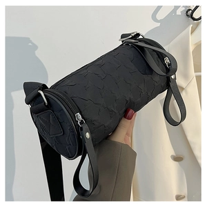 Close-up of black pleated cylinder bag featuring silver zipper and wide nylon shoulder strap