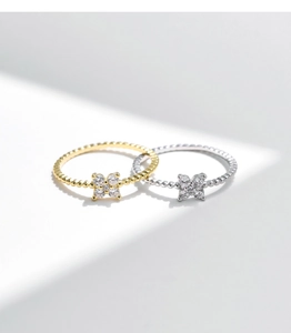 Dettaglio di anelli a quadrifoglio in oro e argento con moissanite scintillante