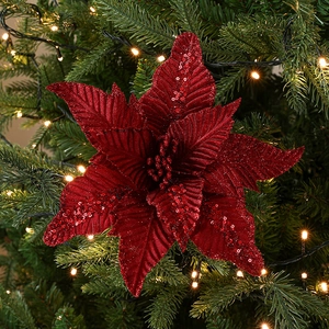 Fleur de poinsettia rouge scintillante décorant un sapin de Noël avec lumières chaudes