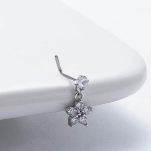 Close-up of flower shaped L-shaped nose stud with shiny zircon stones on white ceramic