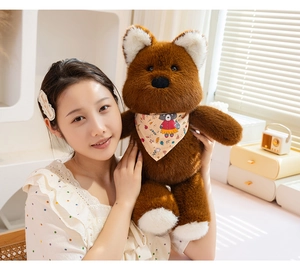 Detailed view of plush teddy bear with floral bandana held by a person in a cozy room