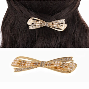 Close-up of golden bow hair clip with pearls and rhinestones on long brown hair