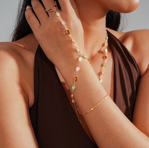 Close-up of golden resin oval pendant necklace with colorful stones on model
