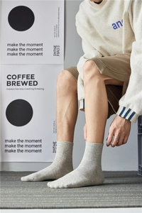 Close-up of grey cotton crew socks for men worn in a casual lifestyle studio setting