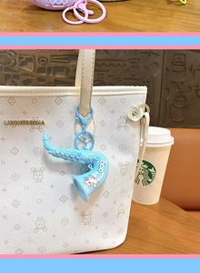 Close-up of a creative blue saxophone keychain pendant hanging on a white tote bag