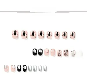 Detail of pink and black spider star press-on nails with shiny finish and art text