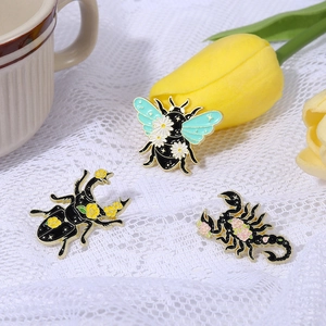 Detail of bee, beetle, and scorpion enamel pins set with daisy flowers on lace