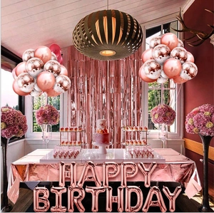 Close-up of rose gold party decor with Happy Birthday balloons and fringe curtain