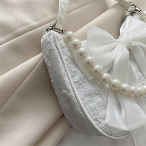 Elegant white floral textured handbag with a large silk bow and pearl chain handle