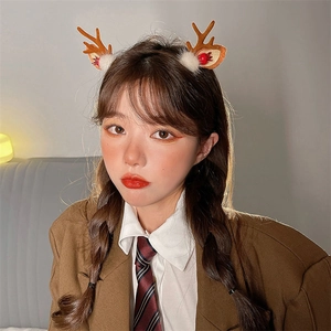 Close-up of reindeer antler headband with red berries and white plush details on a model