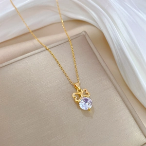 Luxurious gold bow necklace with sparkling round zircon pendant on white silk background