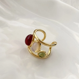 Macro detail of adjustable gold ring with inlaid red, white, and green gemstones