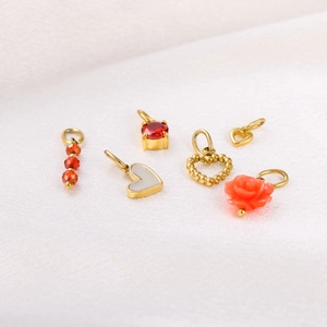 Detail of six gold pendants featuring red stones, white shell and floral designs