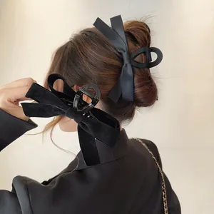 Detail of large black velvet and satin bow hair claw clips for elegant French updo styling