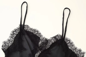 Détail d'un caraco en satin noir avec bordure en dentelle cil et fines bretelles réglables