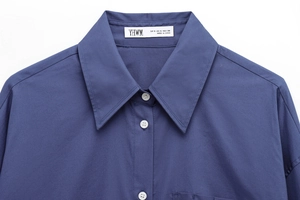 Detail of navy blue long sleeve shirt collar featuring white buttons and fine stitching