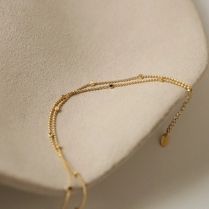 Macro shot of 18K gold plated double layer steel bracelet with square charms