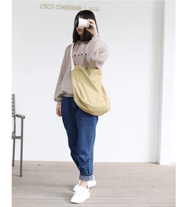 Canvas shoulder bag with adjustable wide strap shown in a minimalist interior setting