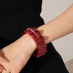 Close-up of red and white agate pattern wavy resin bangle on a fashion model's wrist