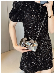 Close-up of silver geometric evening clutch bag with metal chain strap and mirror finish