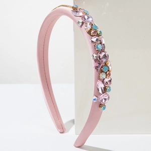 Pink satin headband with sparkling blue and pink crystals on a white geometric stand