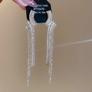 Dettaglio macro di orecchini pendenti in argento S925 con zirconi brillanti e nappe