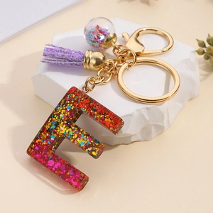 Detail of resin letter E keychain with colorful sequins and purple tassel accessory