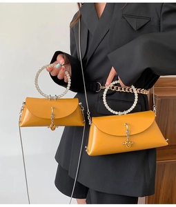Detail of yellow trapezoid handbag featuring a rhinestone handle and golden chain strap