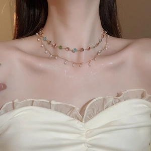 Nahaufnahme einer zweilagigen Goldkette mit bunten Edelsteinen und kleinen Perlenanhängern
