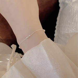 Detailed view of dainty S925 sterling silver beaded bracelet on a woman's wrist