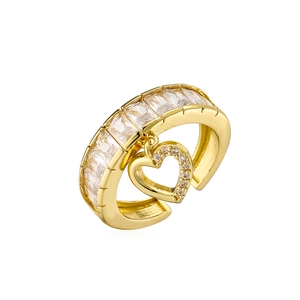Detail of gold-plated heart ring featuring baguette zircons and a dangling heart charm