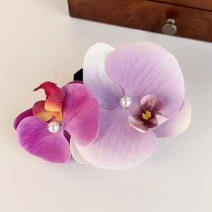 Detailed view of artificial purple orchid petals and white pearls on the hair claw clip